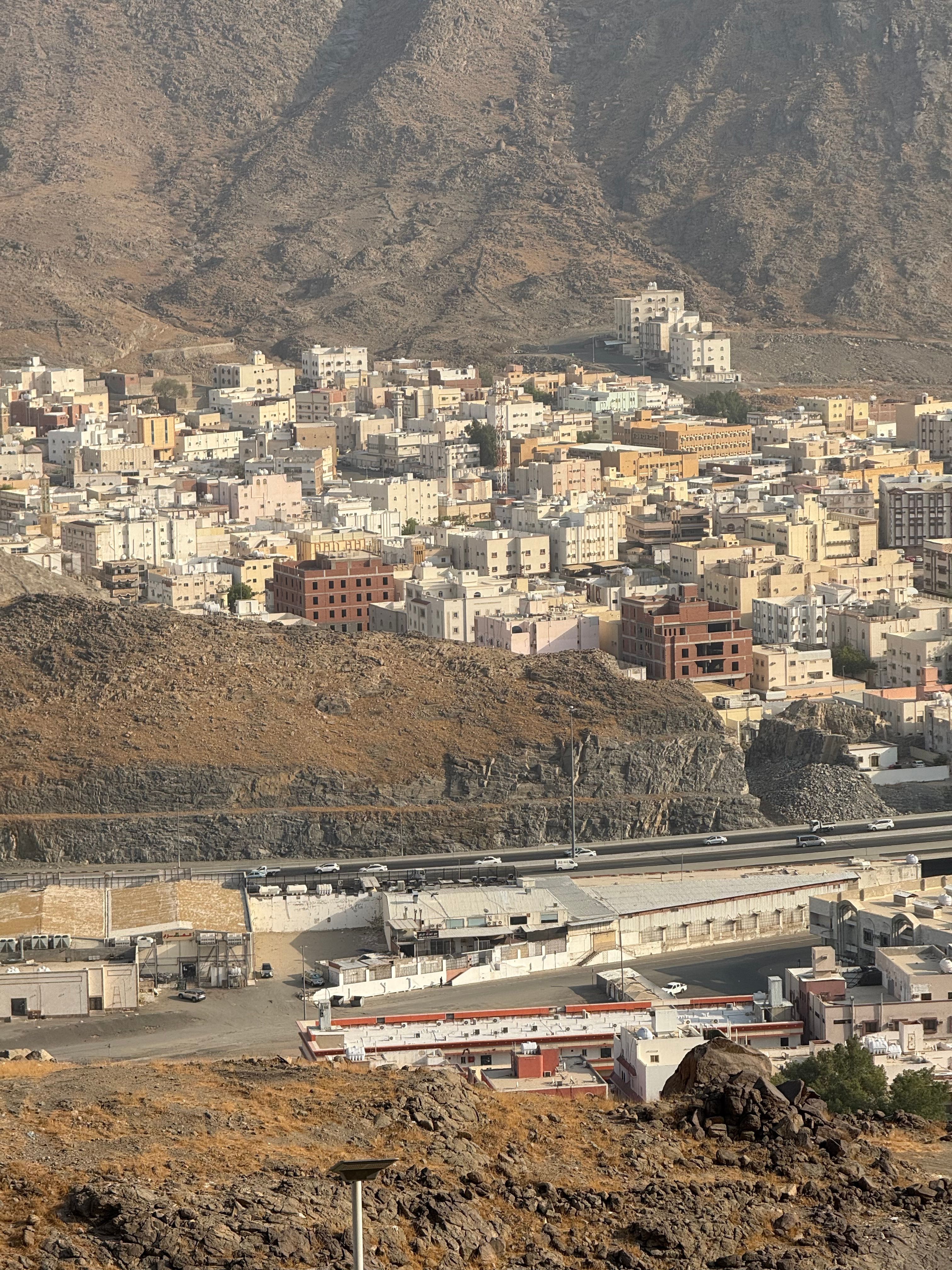Aerial view of Makkah, showcasing urban architecture against a backdrop of majestic mountains.