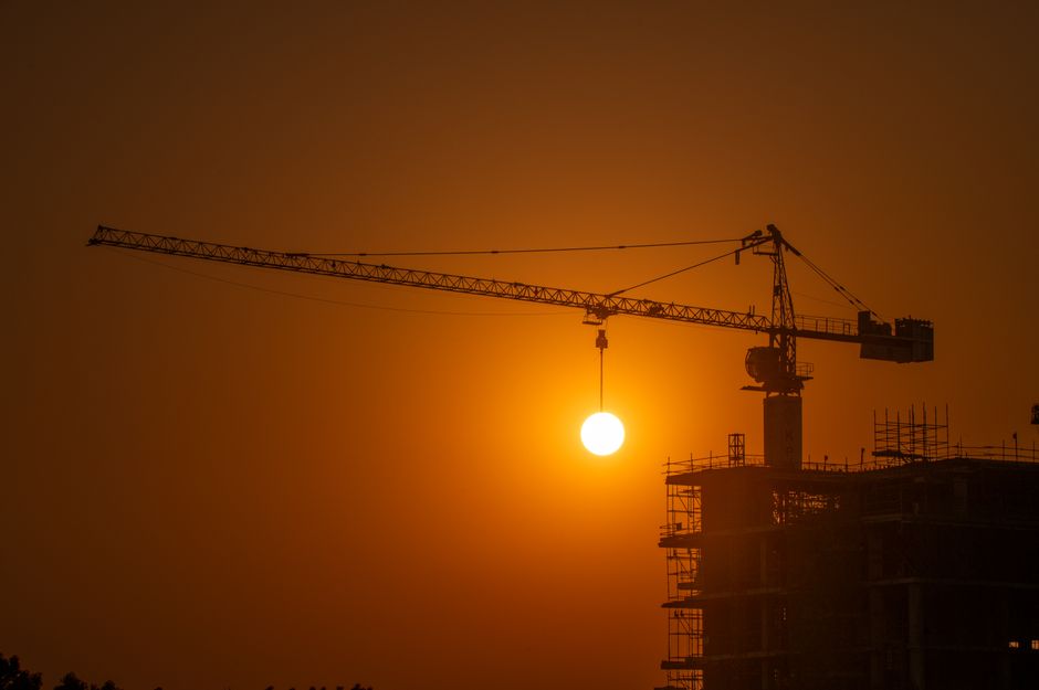Photo: Irshad Ahmad / Pexels A construction crane silhouetted against the Dubai skyline at sunset
