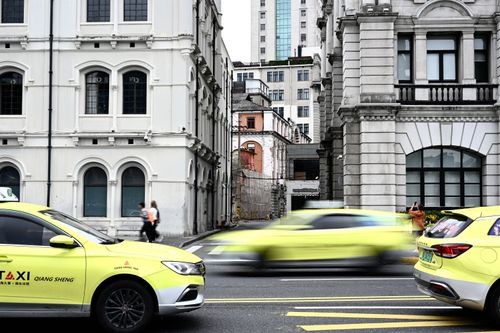 Free Yellow taxis speed through a historic city street, creating dynamic motion in an urban setting. Stock Photo