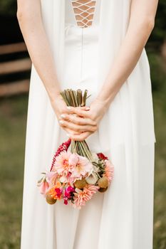 Elegant bridal portrait featuring a bride holding a colorful bouquet behind her back, showcasing luxury wedding style.