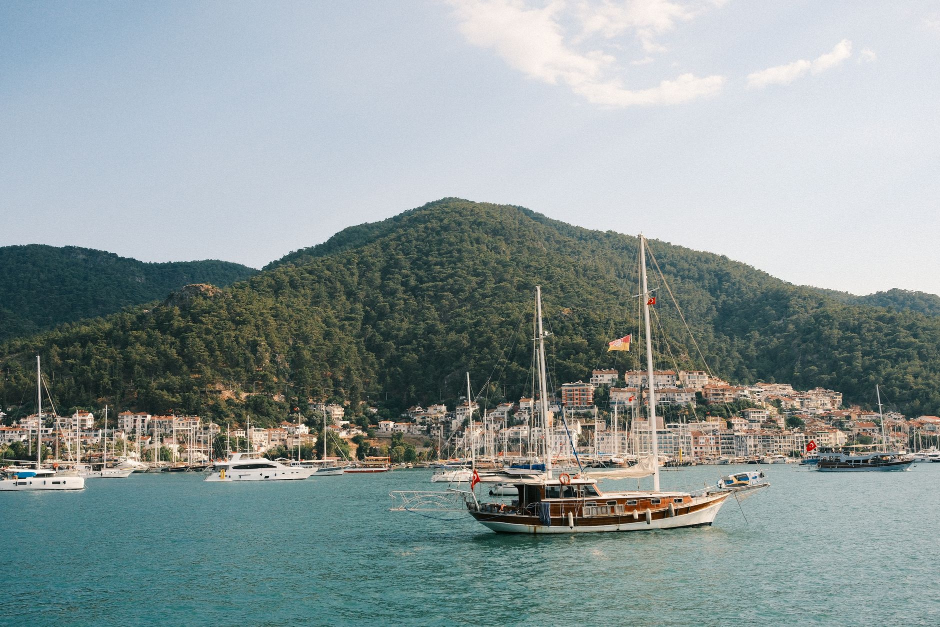A serene view from a luxury yacht deck at sunset overlooking a Mediterranean coastal town.