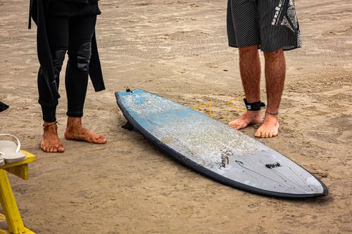 Free Two surfers with a surfboard preparing on the sandy beach of São Paulo, Brazil. Stock Photo