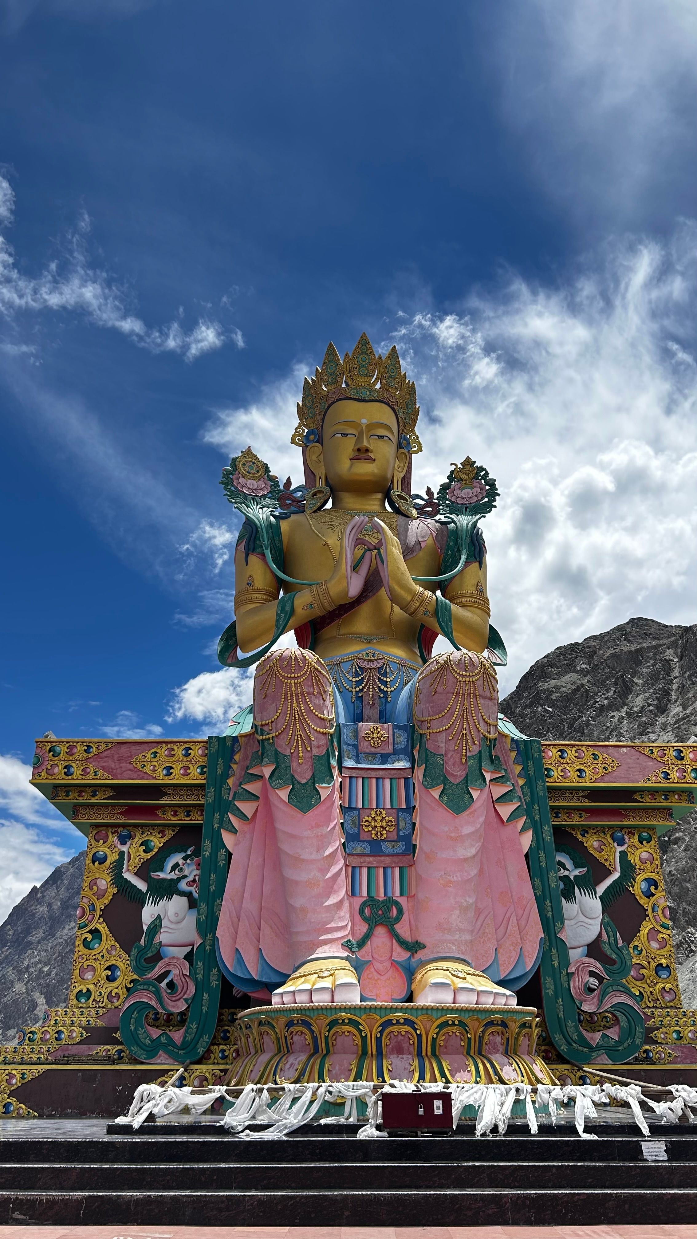 Buddha statue in Ladakh with vibrant colors and mountain backdrop, symbolizing peace and spirituality.