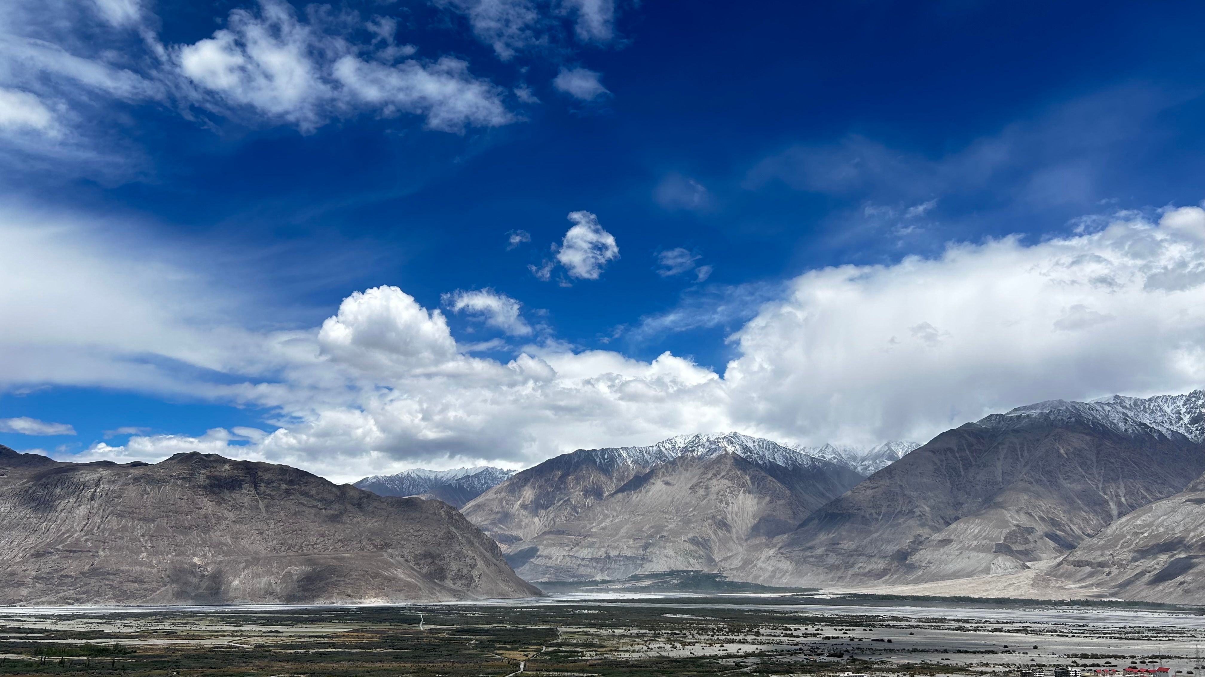 Breathtaking landscape of snow-capped peaks and blue sky in Ladakh, India.