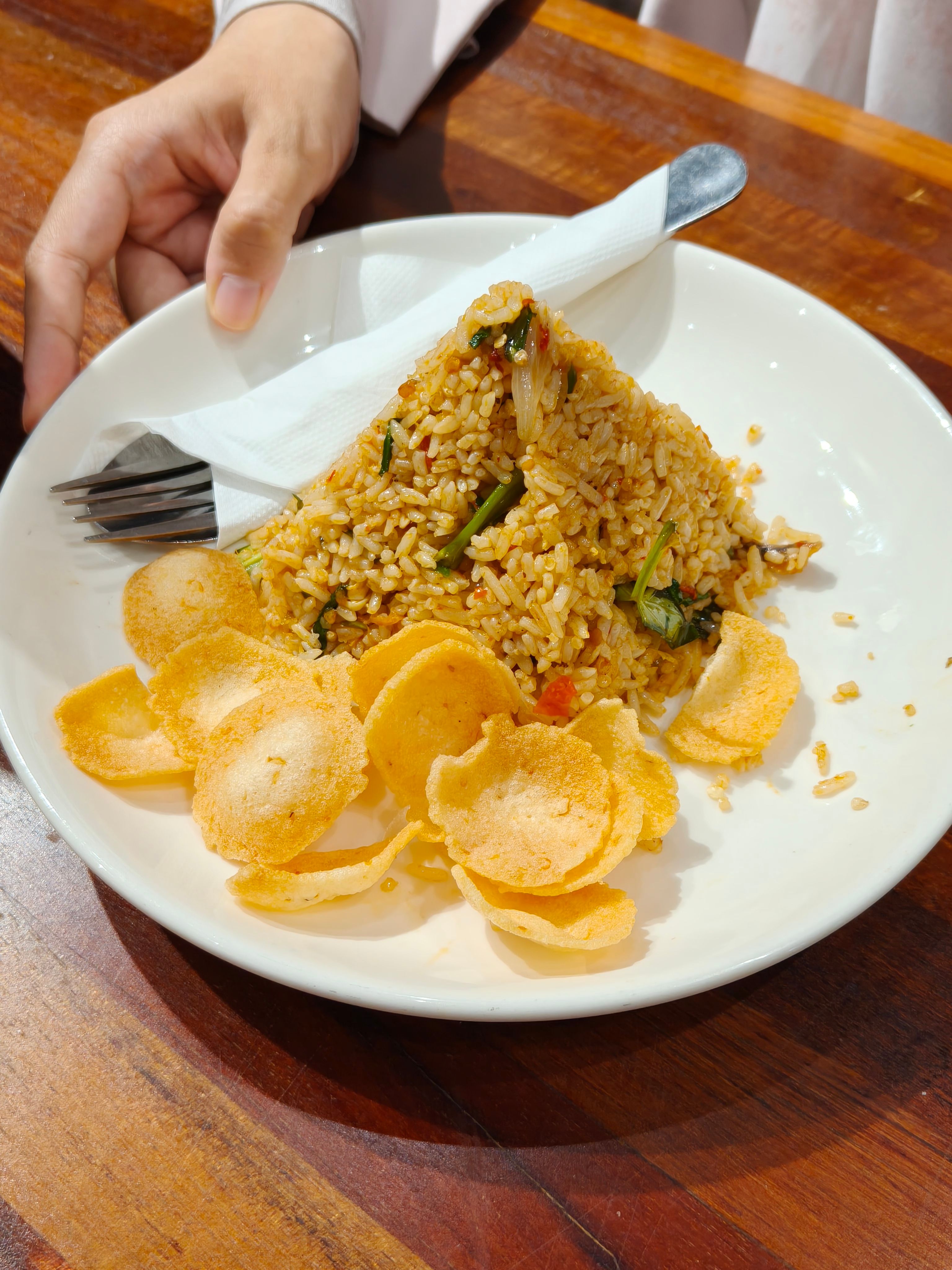 Delicious Malaysian fried rice served with crispy crackers on a white plate. Perfect for Asian cuisine enthusiasts.