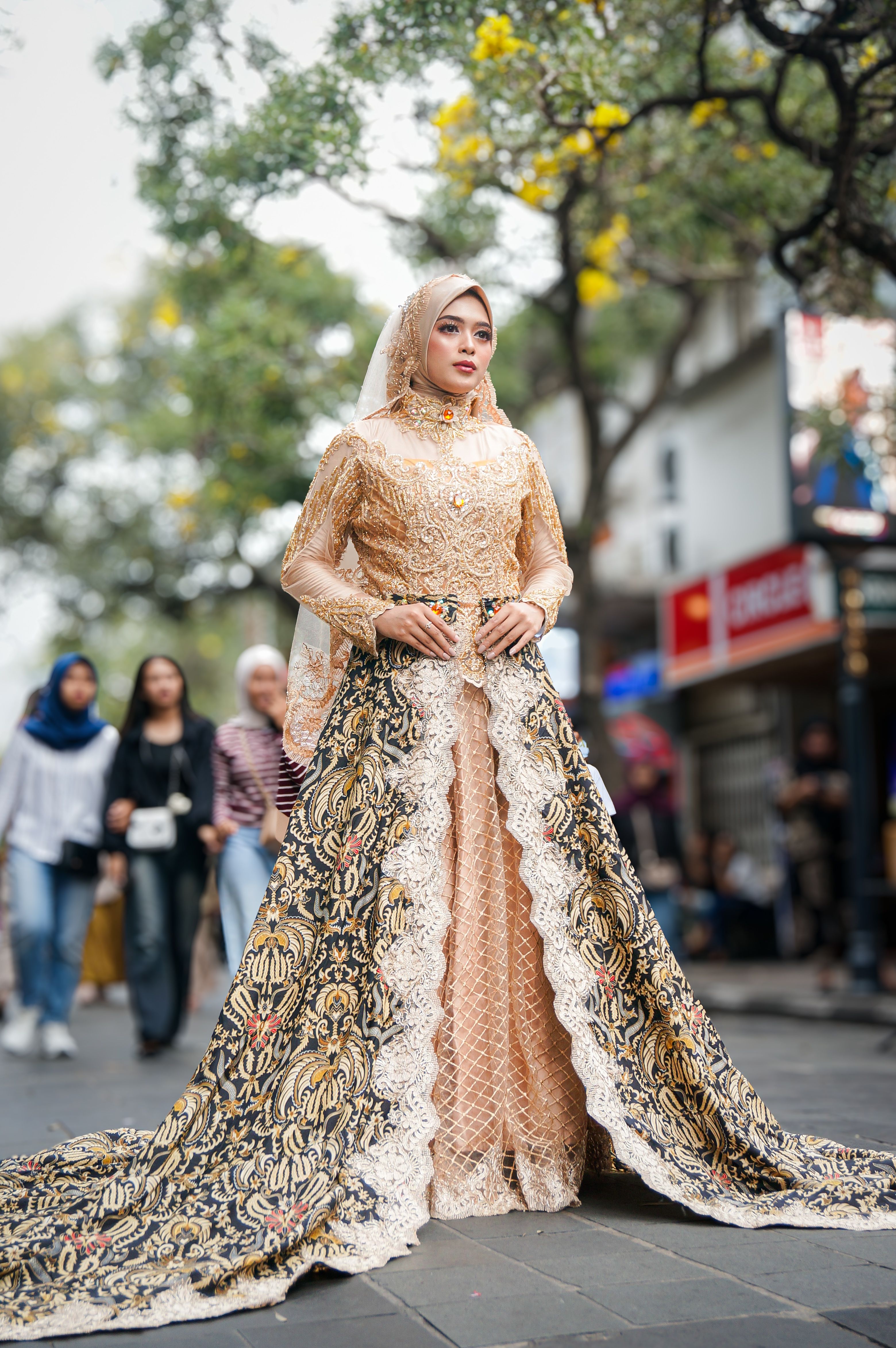 A woman in intricate traditional clothing poses elegantly on a bustling street.