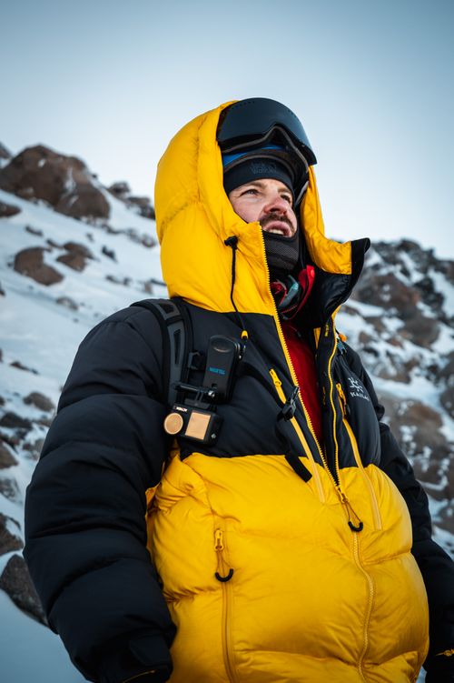 Free Man in yellow winter jacket climbing snowy mountain in Russia. Stock Photo