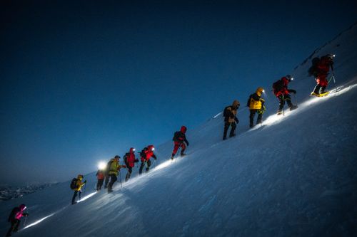 Free A group of climbers ascend Mount Elbrus at night, guided by headlamps, on a steep snowy slope. Stock Photo
