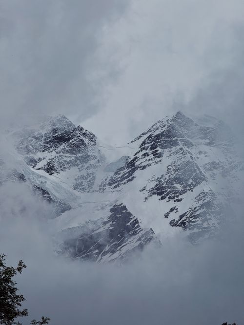 Free Dramatic snow-capped peaks of the Caucasus Mountains enveloped in mist. Stock Photo