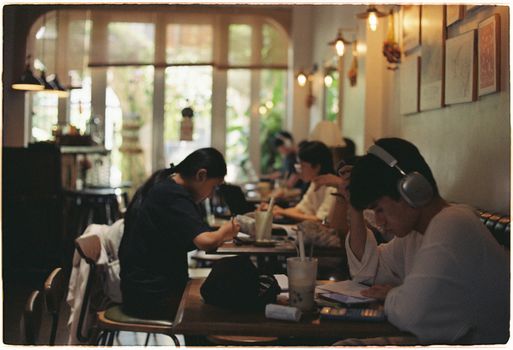 A group of people studying and working in a cozy, well-lit cafe setting.