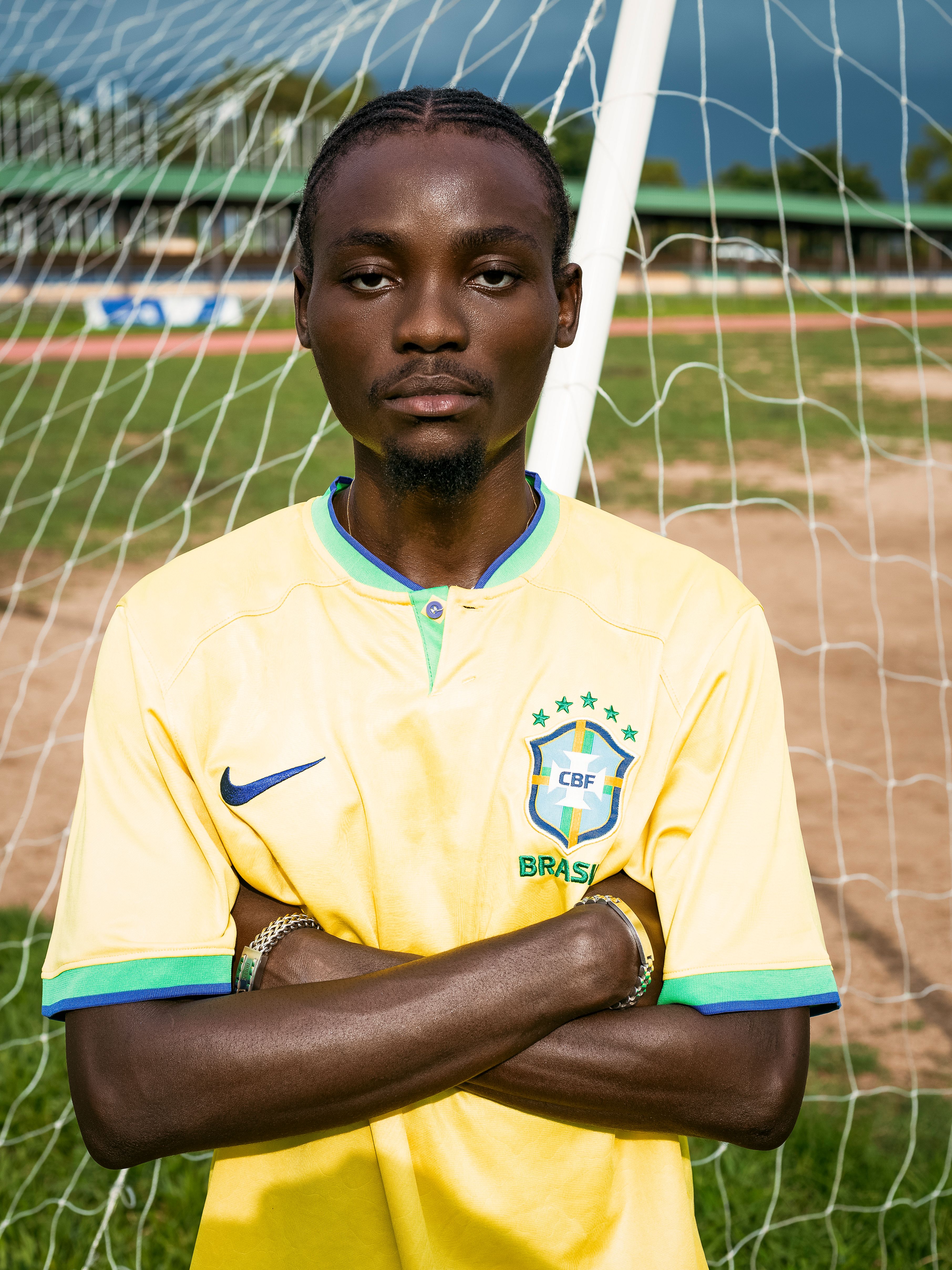 Young soccer player poses confidently in a yellow jersey on an outdoor field.
