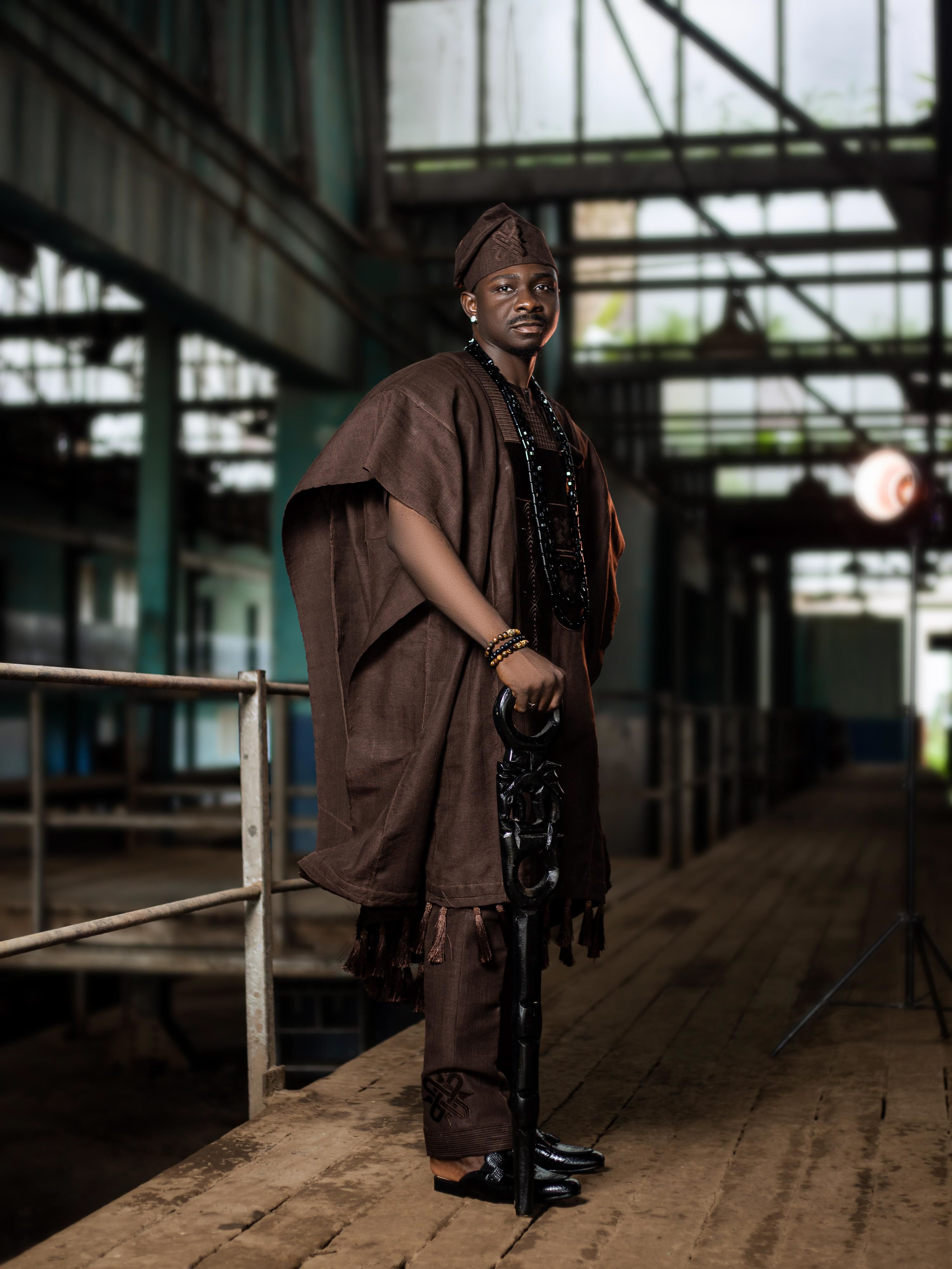 Portrait of a man in traditional attire standing in an industrial interior.