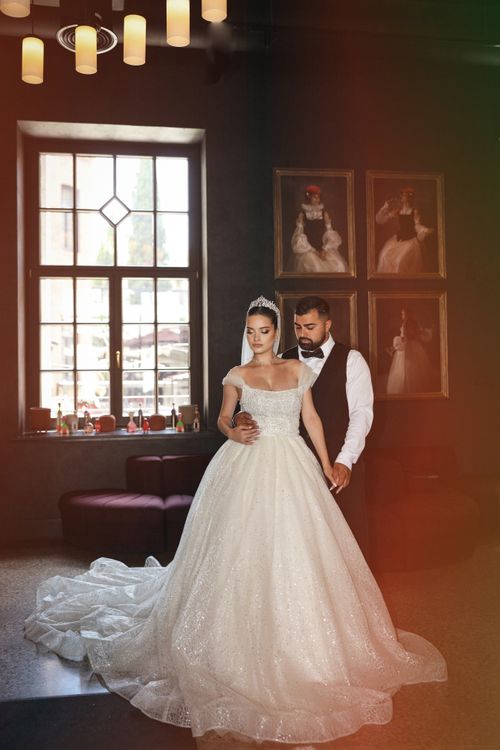 Free Bride and groom pose elegantly indoors in a classic wedding setting. Stock Photo