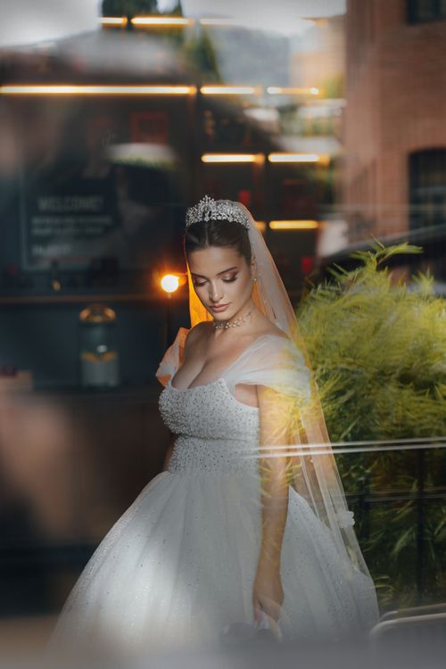Free Beautiful bride in a stunning gown gazing down in an intimate indoor setting. Stock Photo