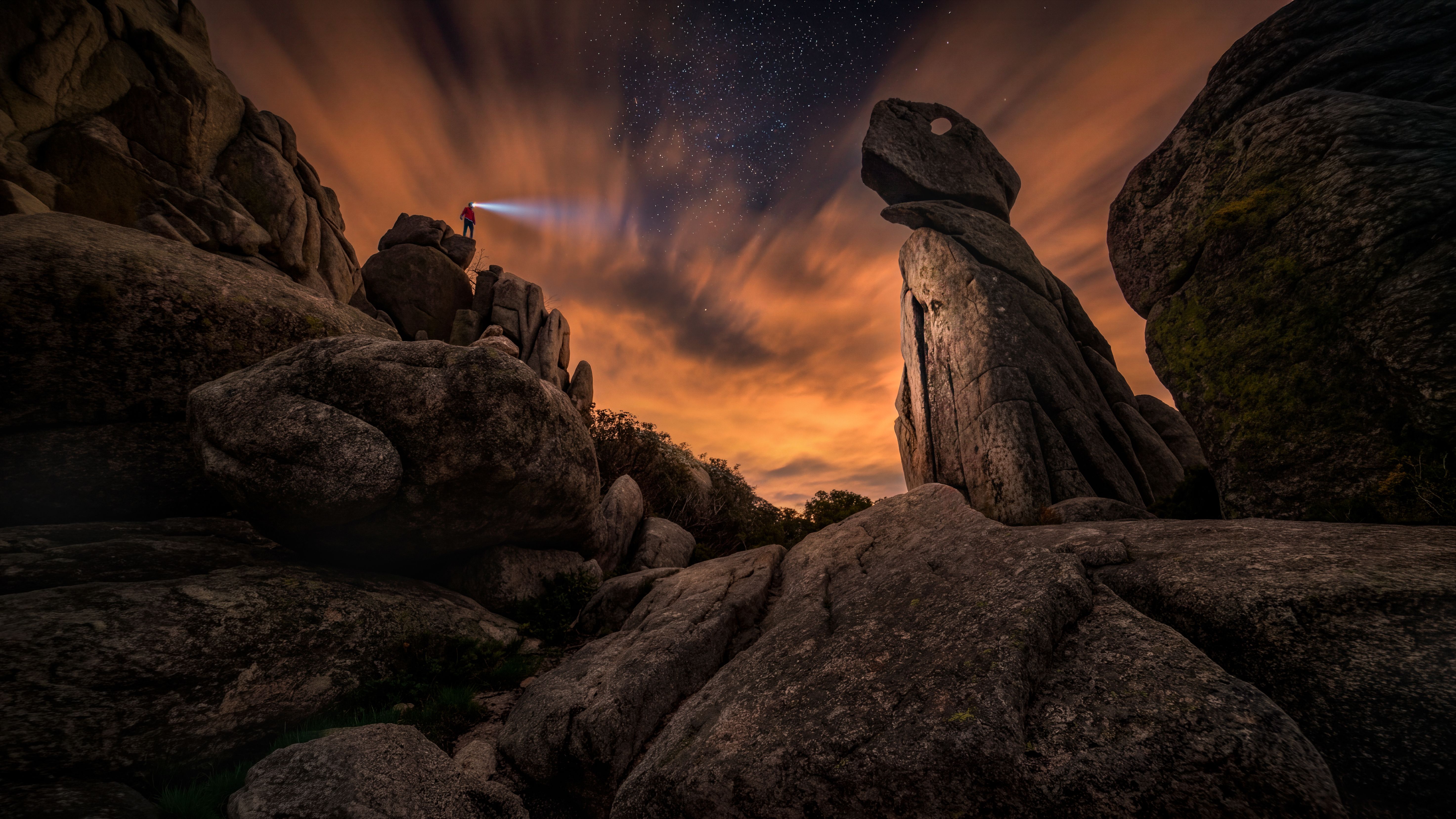 A hiker's headlamp beam reaching across a dark rocky landscape