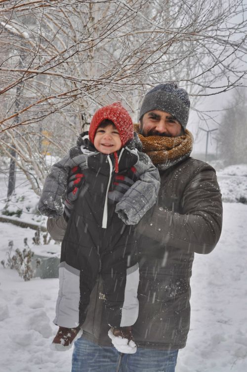 Free Father holding child in snowy winter park, both smiling warmly dressed in cozy outerwear. Stock Photo