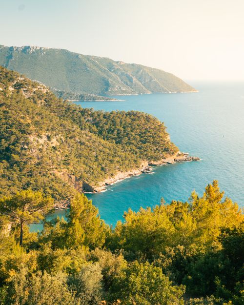 Free Stunning view of lush green cliffs meeting the blue Mediterranean Sea under sunny skies. Stock Photo