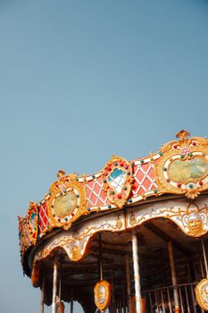 A classic carousel with ornate details set against a clear blue sky, evoking nostalgia and whimsy.
