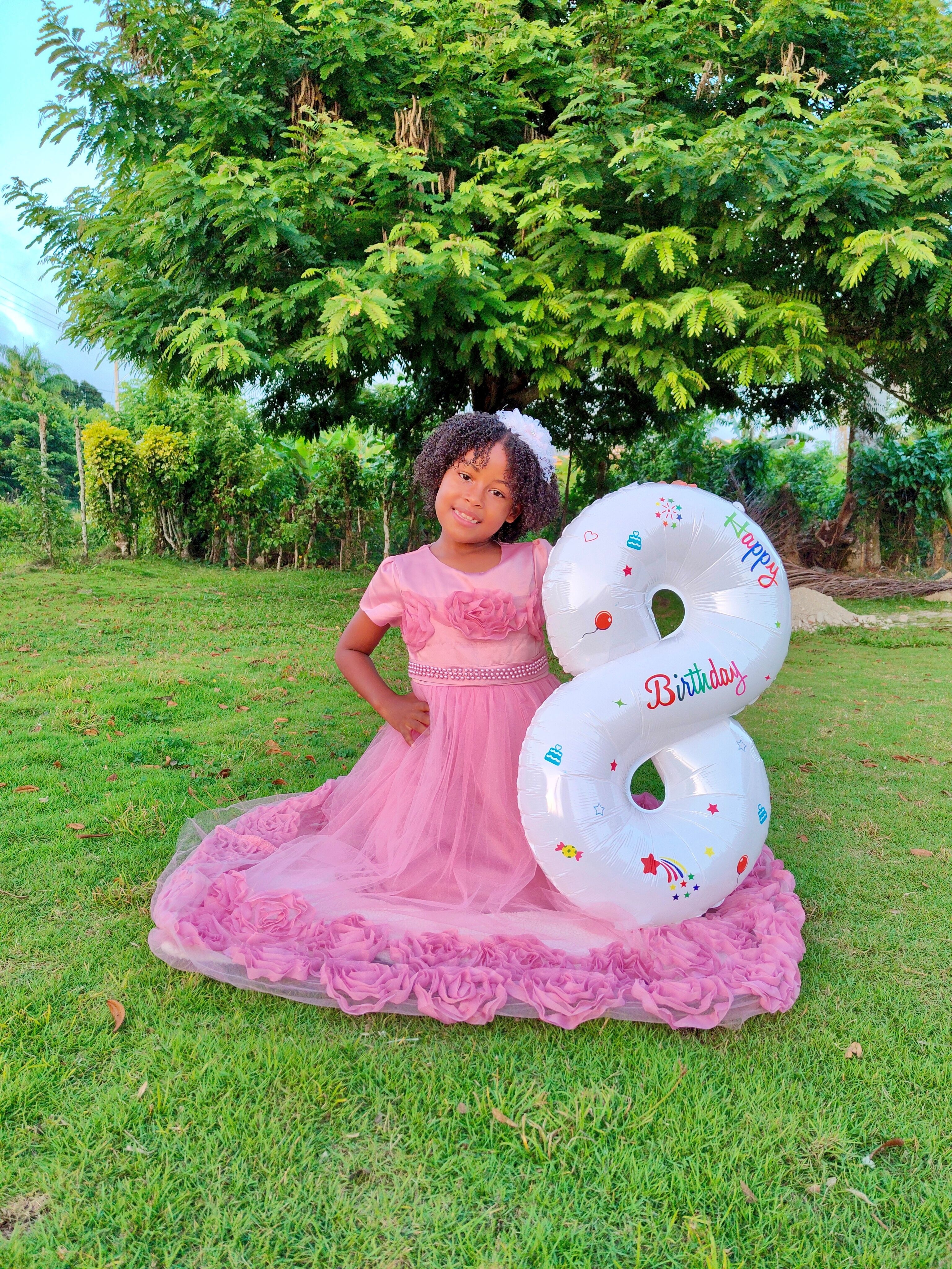 Fotomural Niña joven celebrando su octavo cumpleaños con un globo al aire libre en un jardín.