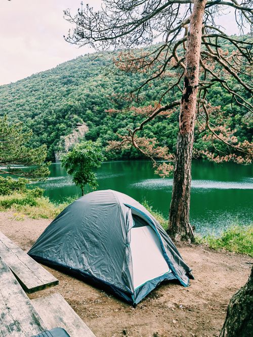 Free A peaceful tent setup by a serene mountain lake, perfect for camping enthusiasts. Stock Photo