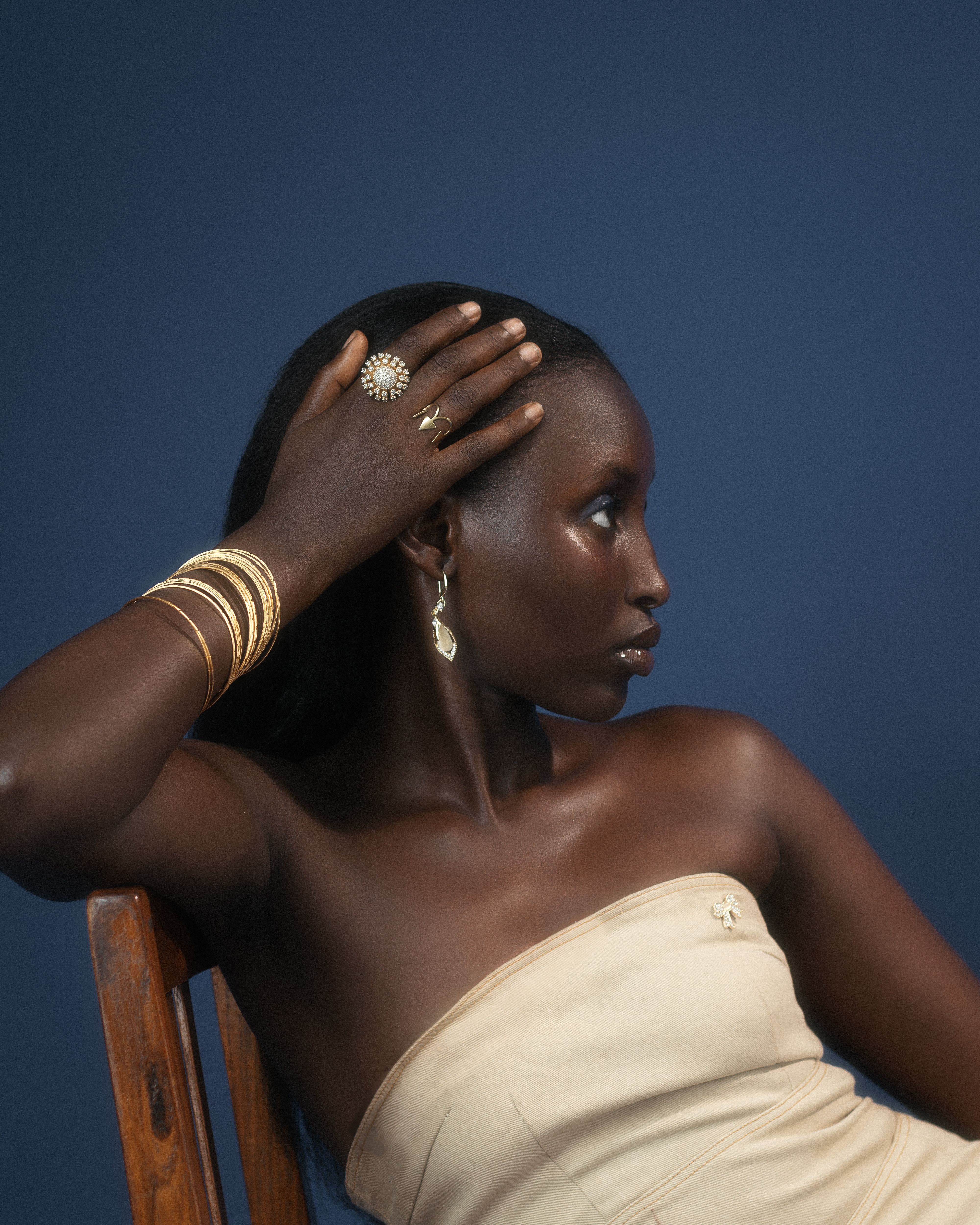 Beautiful portrait of a woman wearing gold jewelry, set against a deep blue background.
