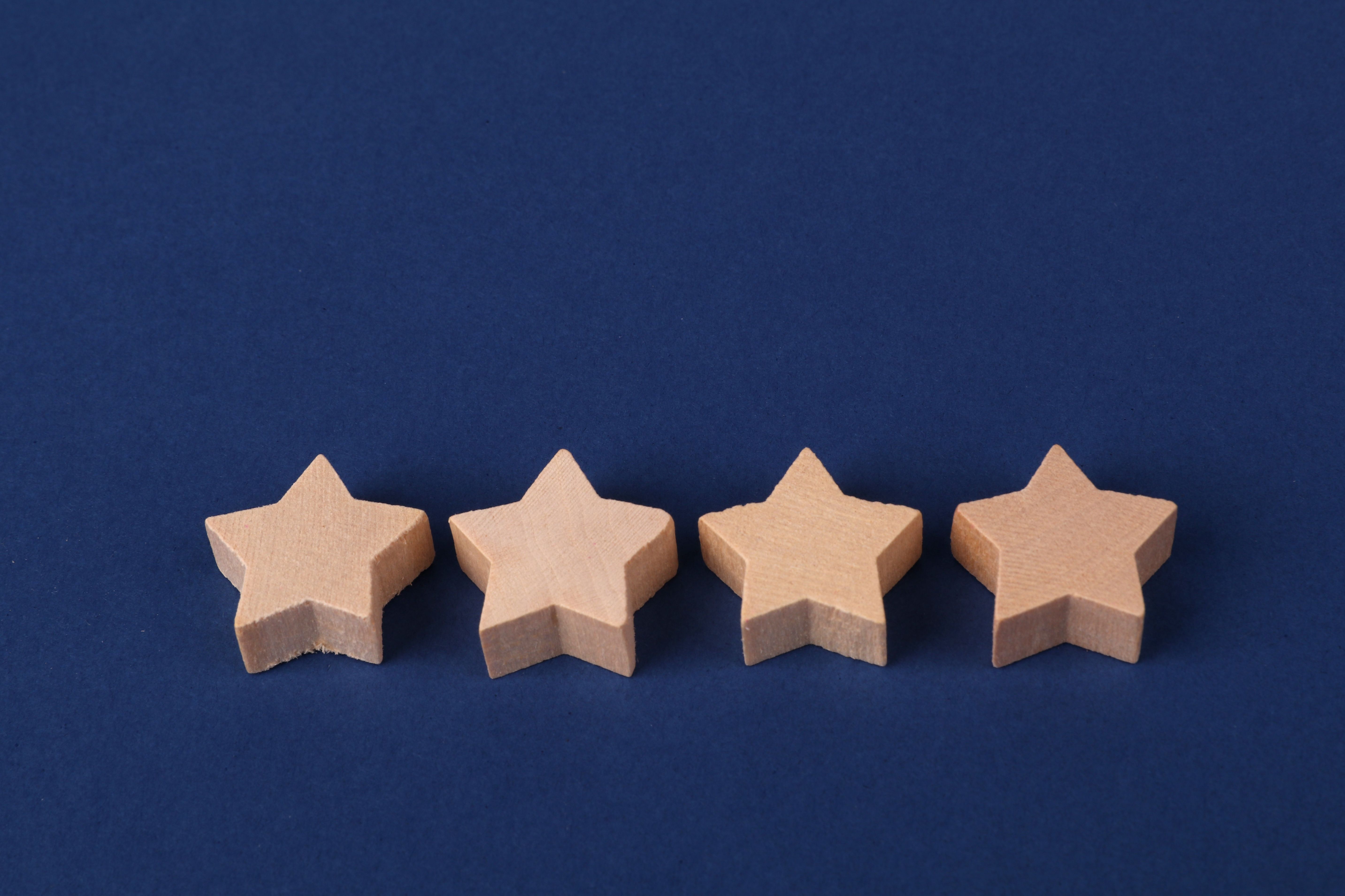 Minimalist photo of four wooden star shapes arranged on a navy blue surface.