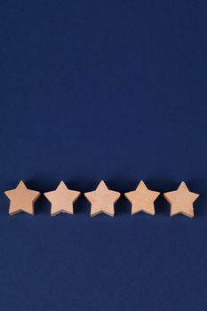 Five wooden stars lined up on a blue background, symbolizing a rating or quality concept.