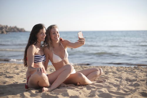 Women In Bikini Sitting On Beach Sand