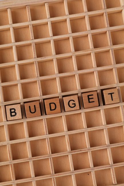 Wooden blocks arranged to spell 'Budget' on a lattice background, emphasizing financial planning.