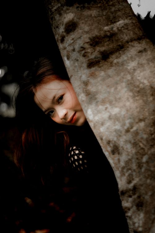Free A woman smiling as she peeks from behind a tree in Kuningan, Indonesia. Stock Photo