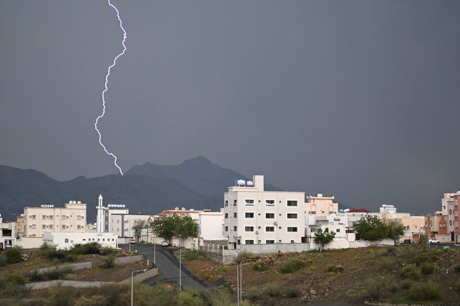Dramatic lightning bolt over Muhayil city with mountains and storm clouds in Aseer Province, Saudi Arabia.