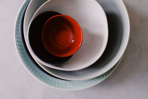 Four nested stoneware bowls in celadon, white, charcoal and red from above