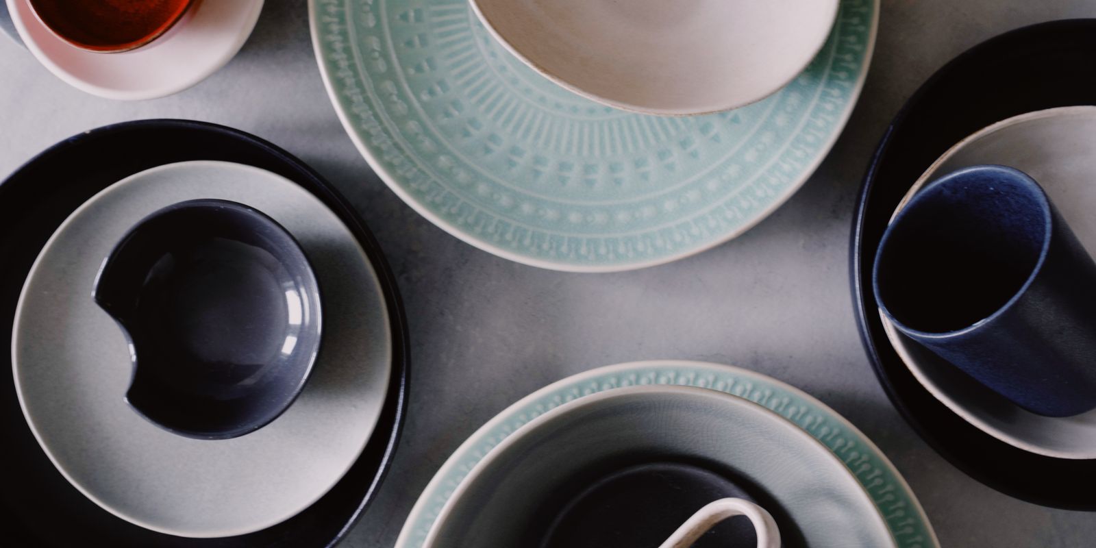Colorful ceramic plates, mugs and bowls arranged on a table
