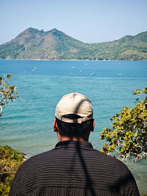 Free A man gazes at the scenic coastline of West Nusa Tenggara, Indonesia, blending into a serene natural landscape. Stock Photo