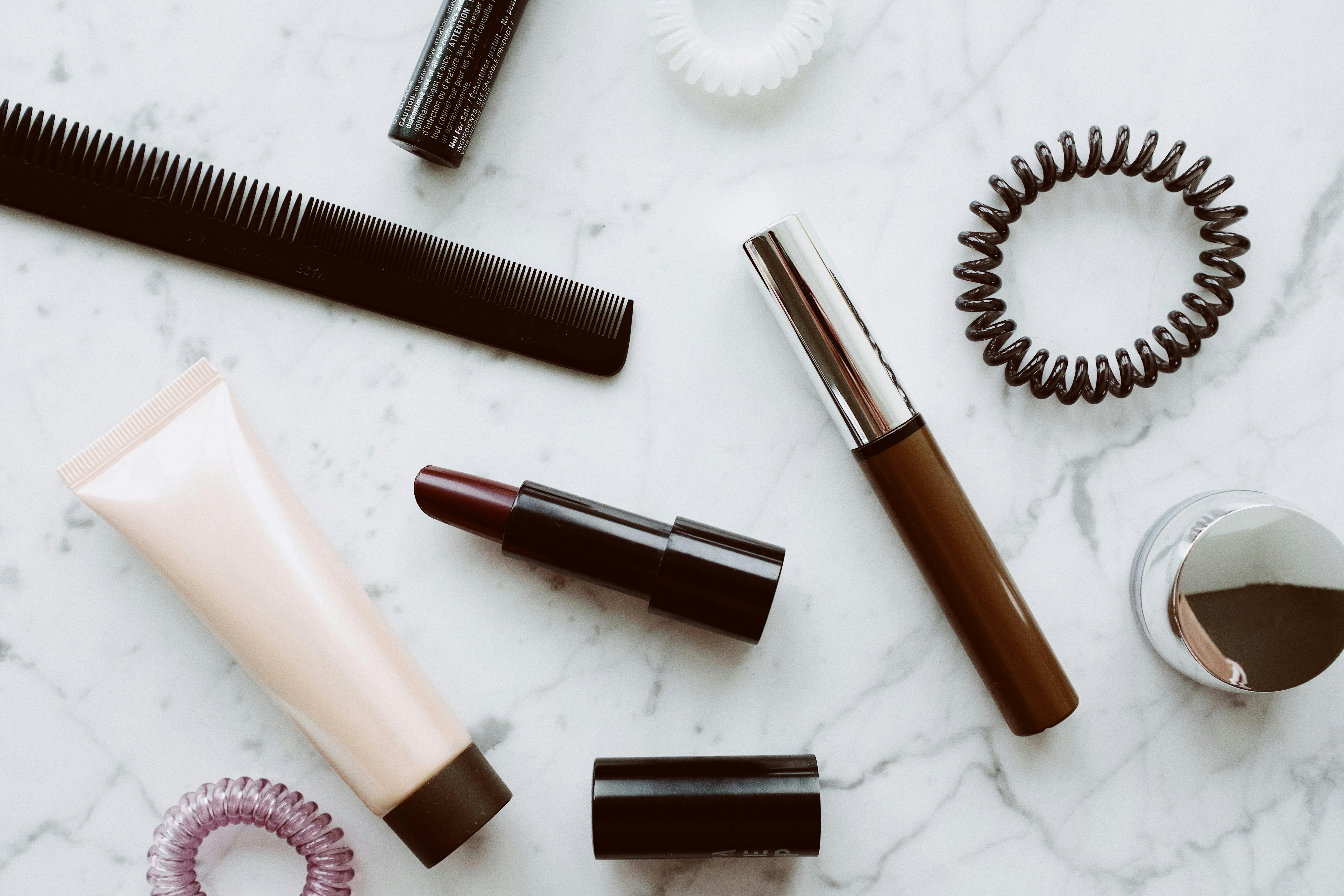 Free Flat lay of various cosmetics and accessories on marble, showcasing a modern beauty theme. Stock Photo