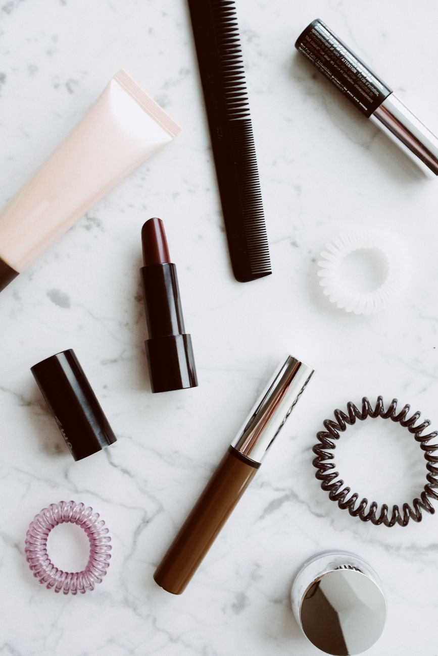 Top view of various cosmetic products for makeup and beauty style composed on white background with marble pattern