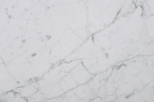 Smooth white marble surface showing natural veining and texture, perfect for design backgrounds.