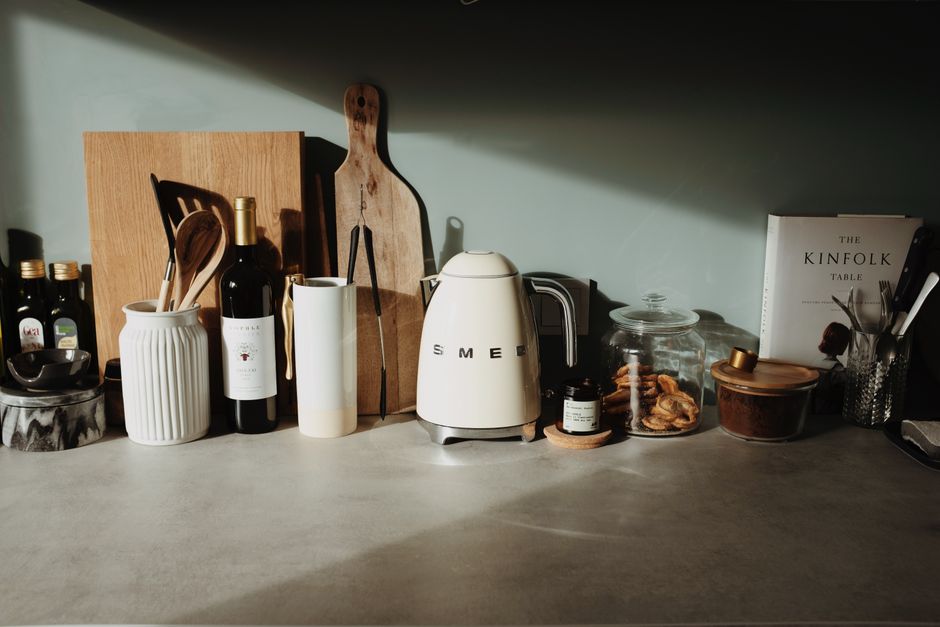 Various glass and ceramic bowls stylish electric kettle cutting boards and kitchen utensils locating on stone counter against gray wall in cozy kitchen - High Quality Performance Evaluation