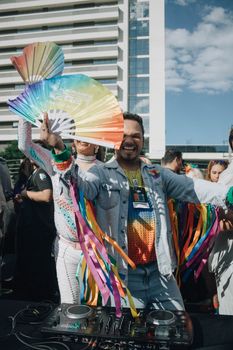 Joyful outdoor event featuring a DJ and colorful rainbow fans in a lively setting.