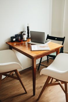 A warm and inviting home office setup featuring a wooden table, chairs, and a laptop for remote work.