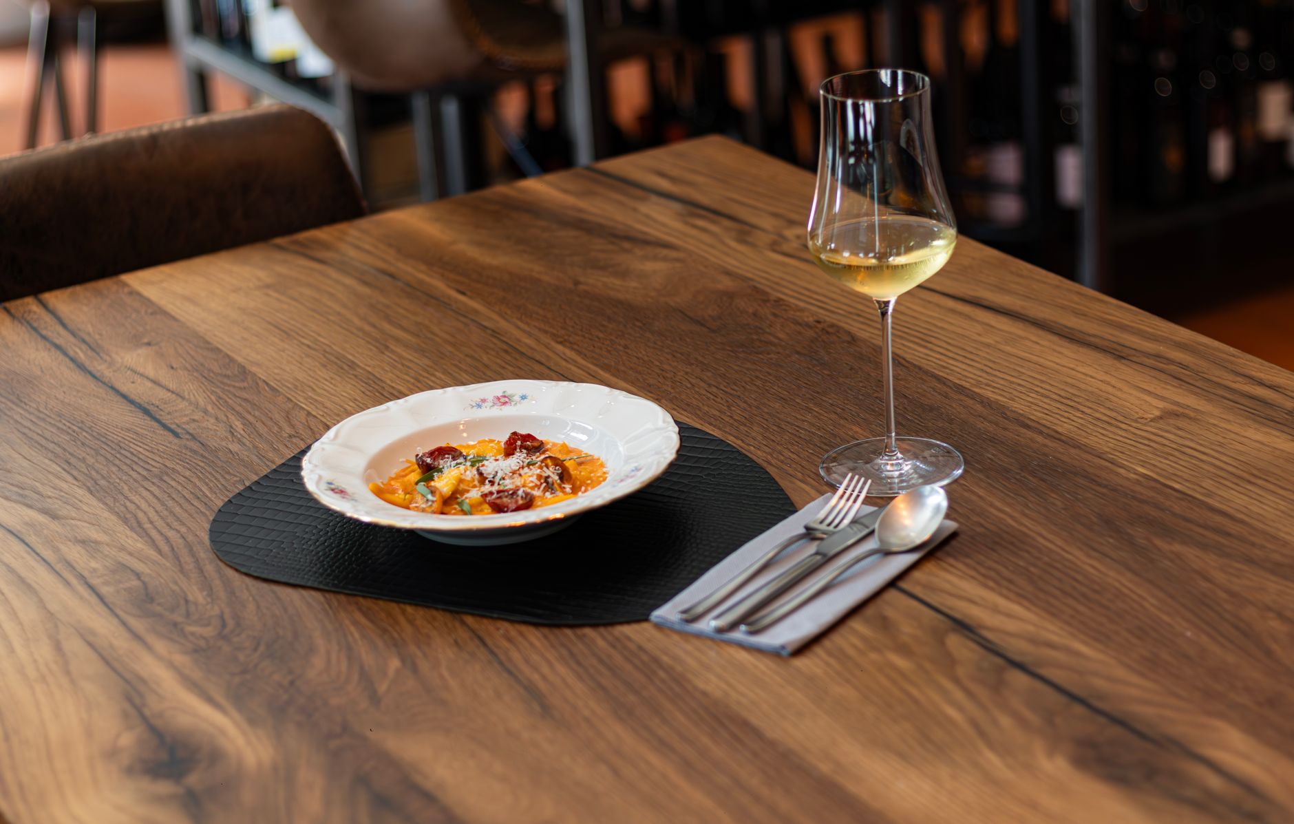 Elegant presentation of Italian dish with wine on wooden table in a cozy setting.