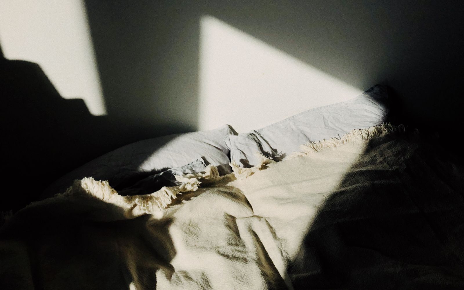 A cozy bedroom with warm morning sunlight on the bed and blanket