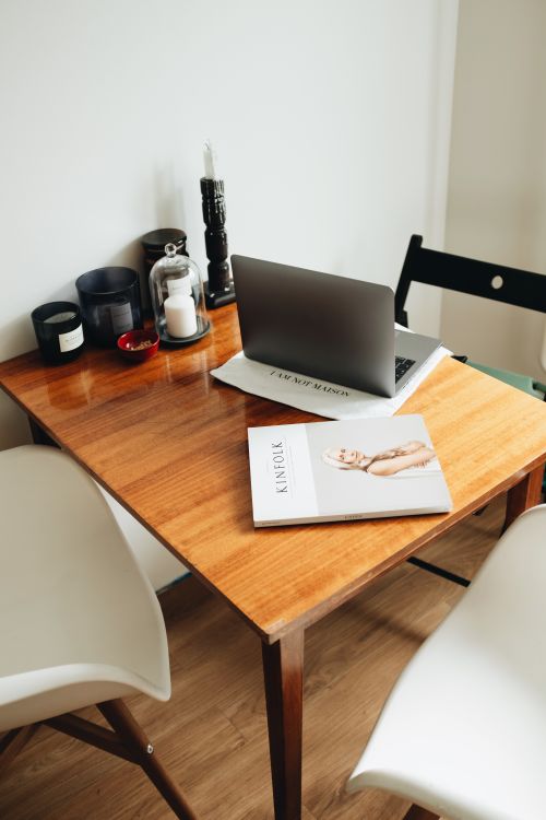 Free Warm indoor workspace featuring a wooden table, laptop, and decor for a comfortable office setting. Stock Photo