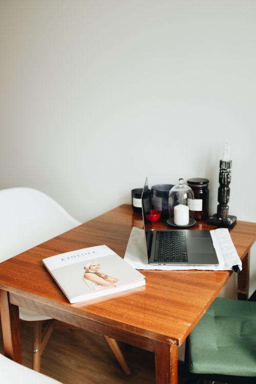 Free A stylish indoor workspace with a laptop, candles, and a wooden table creating a cozy atmosphere. Stock Photo