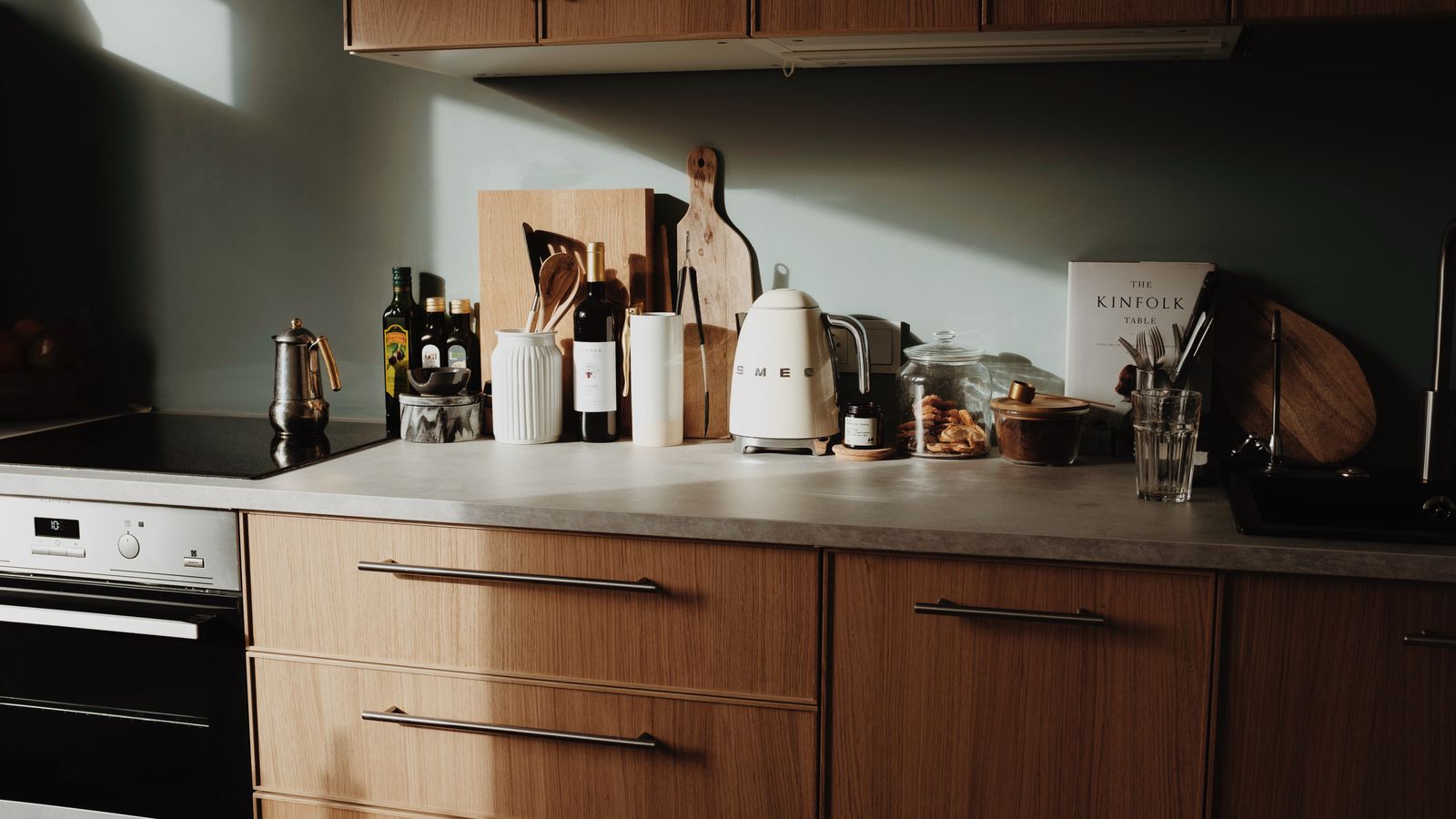 A white kettle and kitchen utensils on a sunlit counter