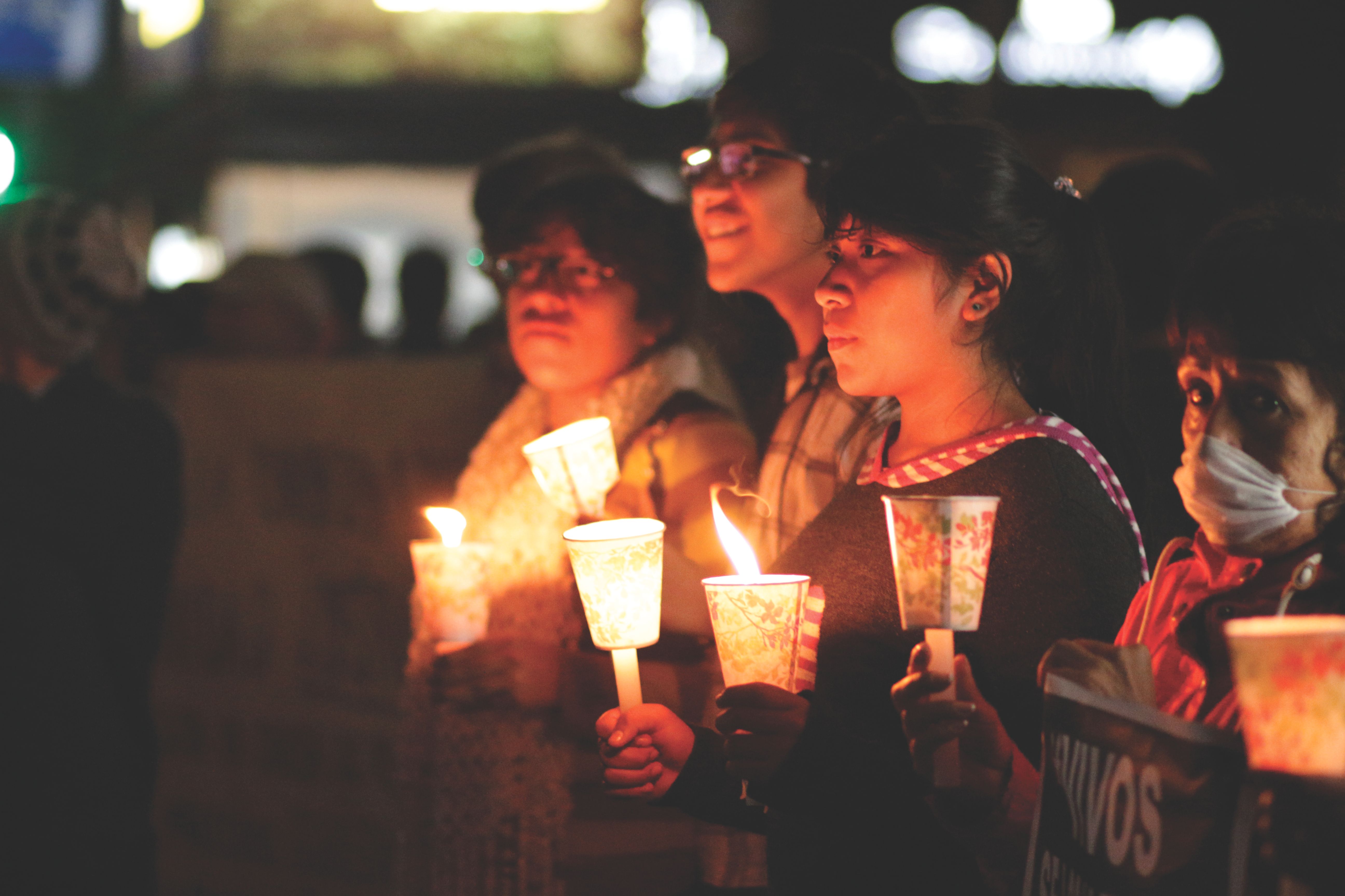 young adults gathered in a circle outdoors with open books and candles