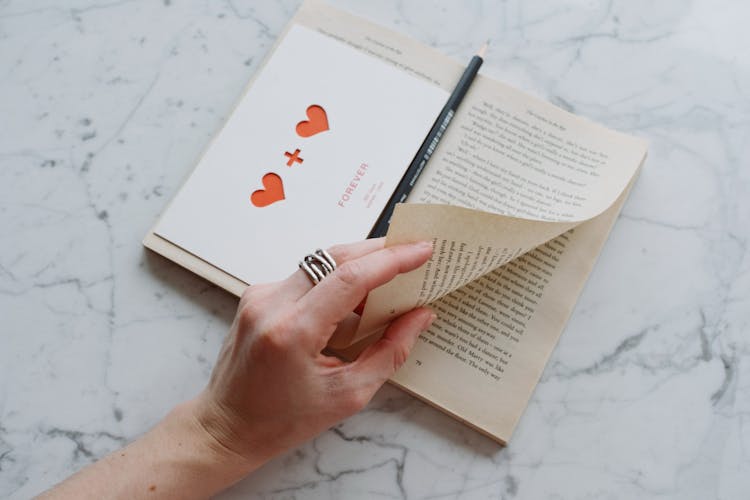 Anonymous Crop Person Reading Book On Marble Surface