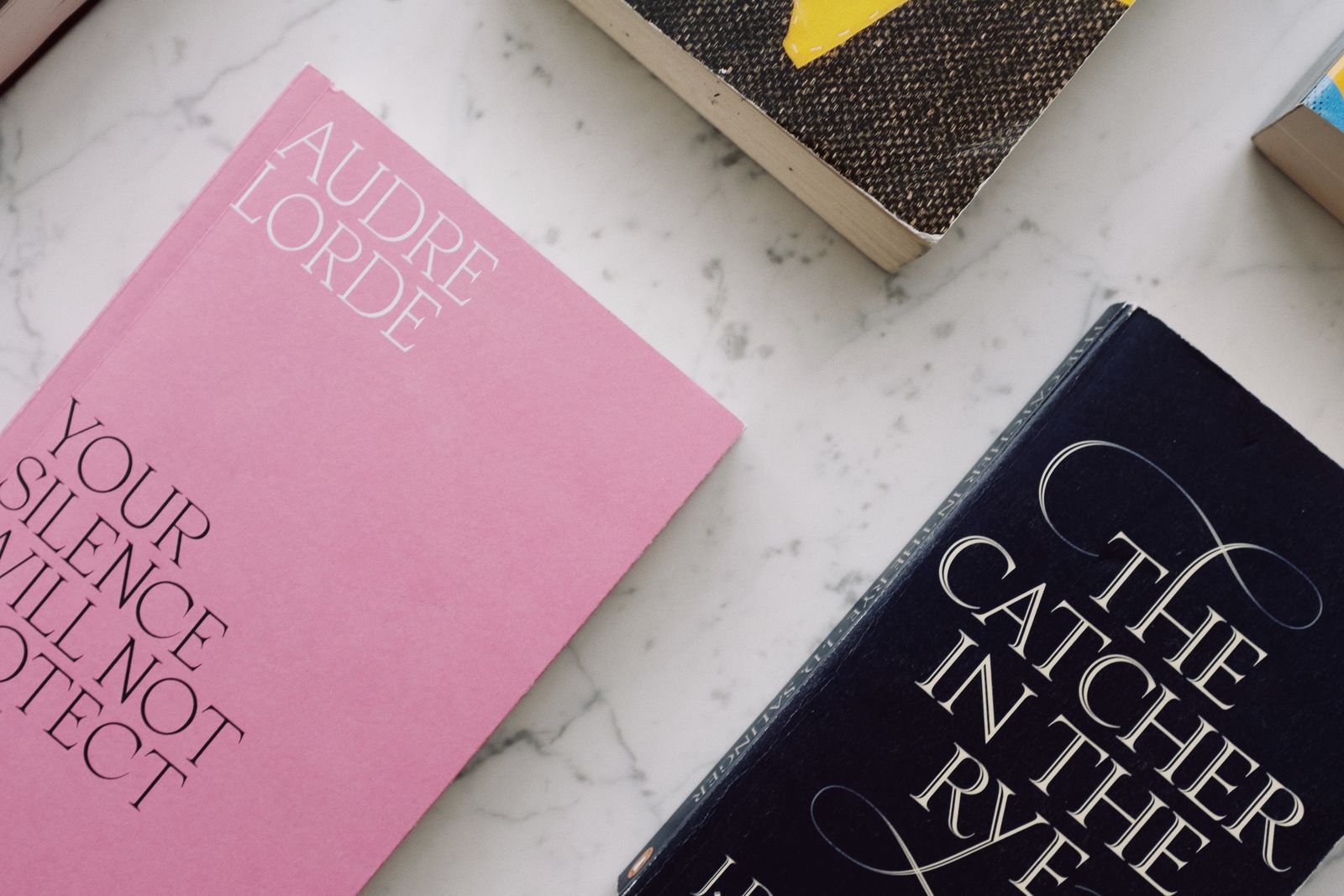 Books with designed covers laid out on a pale marble surface