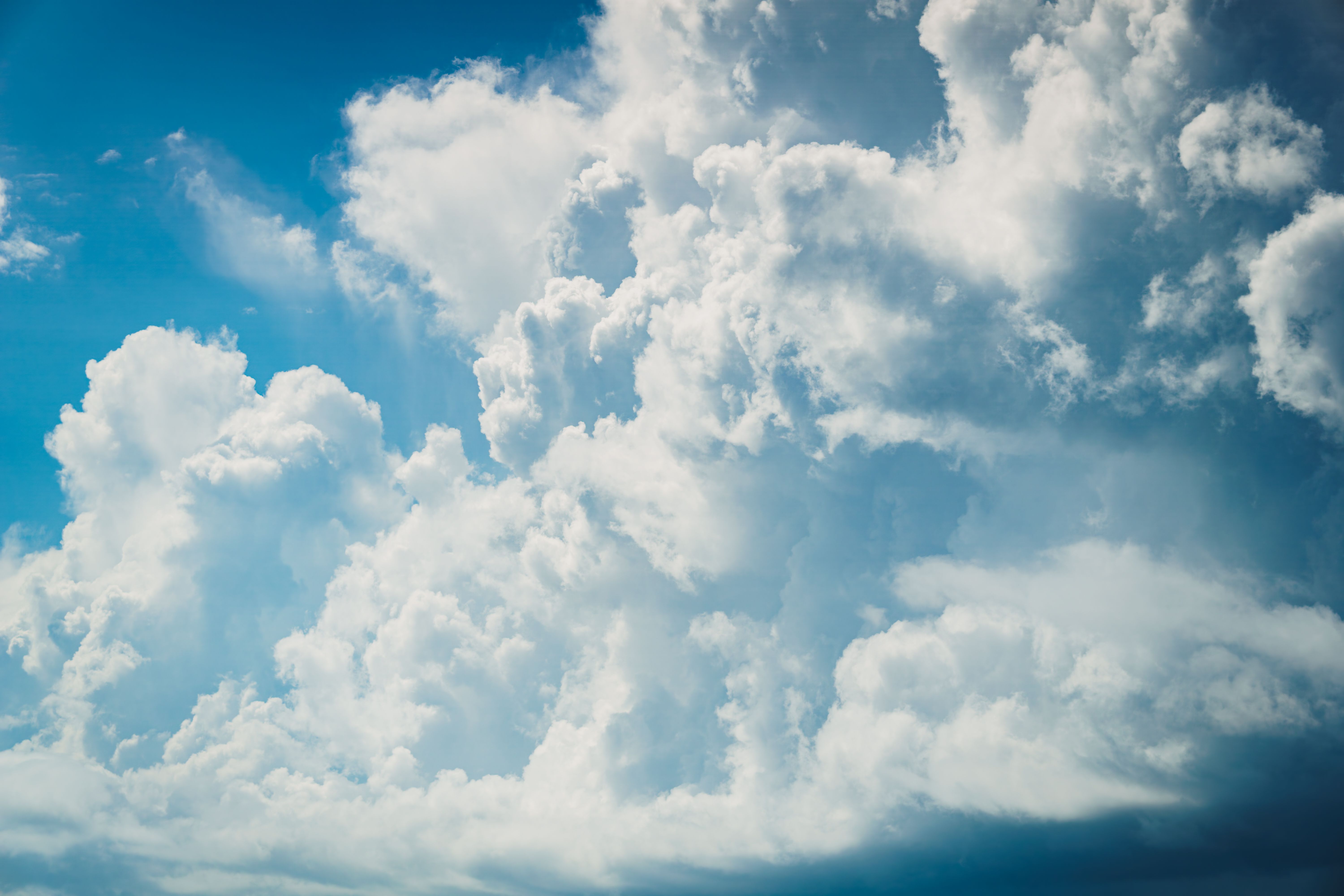 A stunning view of fluffy cumulus clouds against a clear blue sky during daytime.