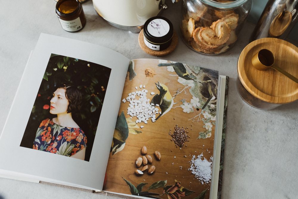 Open cookbook with jars and kitchen ingredients viewed from above